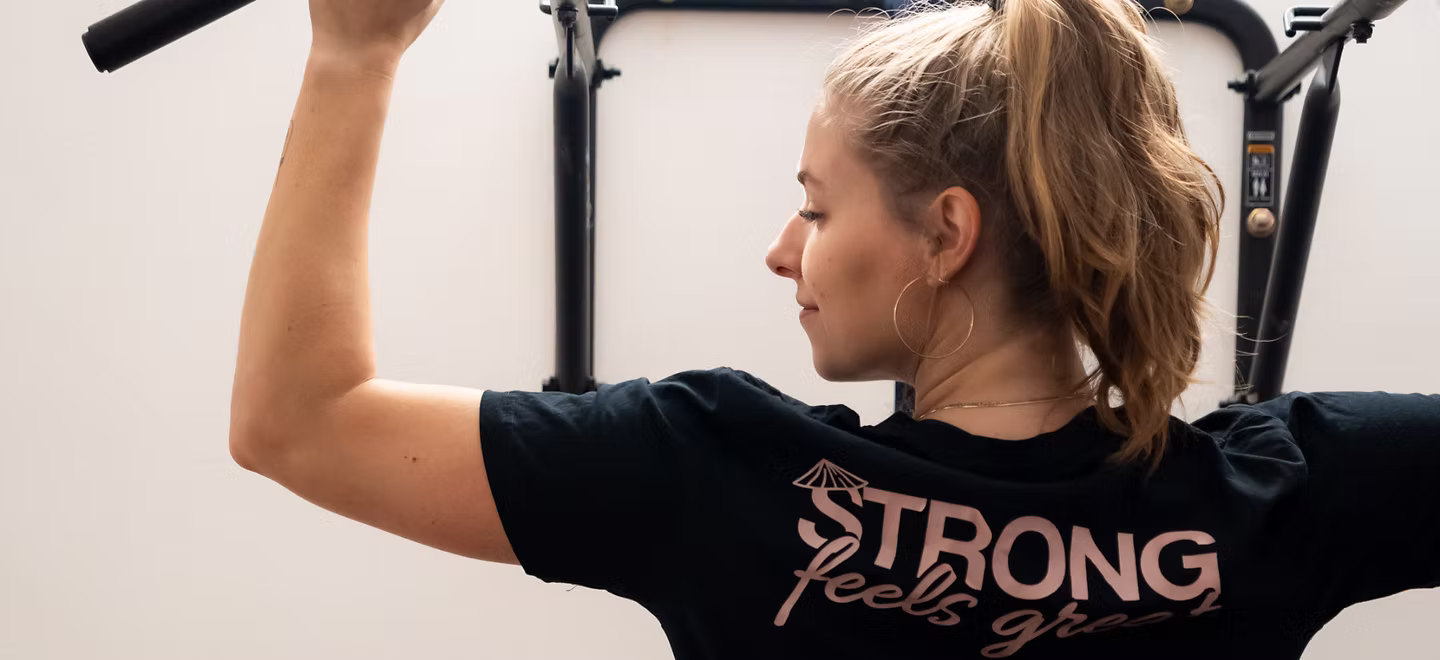 Woman lifting at the gym in a Strong Feels Great shirt